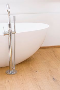 a white bath tub sitting on top of a wooden floor