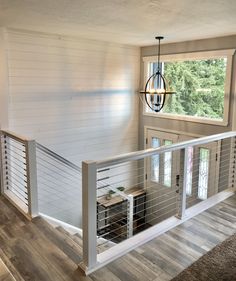 the inside of a house with white walls and wood flooring, stairs leading up to a second story window