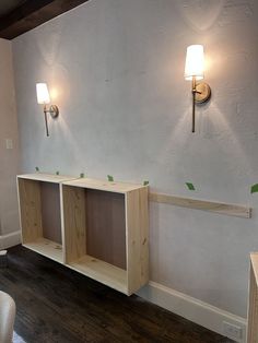 a room that has some shelves on the wall and two lights above it with green tape