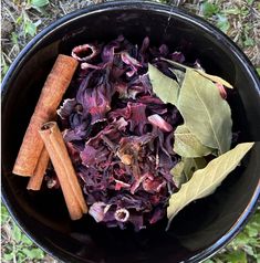 a black bowl filled with red cabbage and cinnamon sticks next to some leaves on the ground