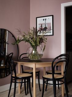 a dining room table with chairs and a vase filled with flowers