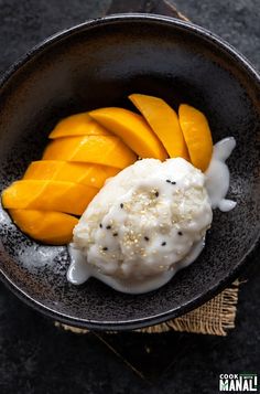 a bowl filled with ice cream, mango slices and some kind of fruit on top