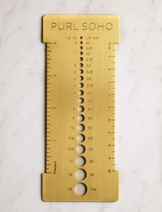 a gold ruler with holes on it sitting on a marble surface