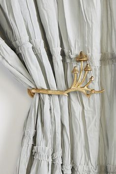 a curtain with gold metal decorations hanging from it's side, on a white wall