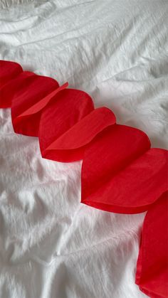 red curved pieces of paper sitting on top of a white bed sheet covered in sheets