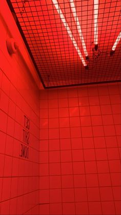 a bathroom with red light coming from the ceiling and tiled walls, along with white tile flooring