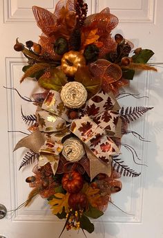 a wreath is hanging on the door with autumn leaves and acorns in it