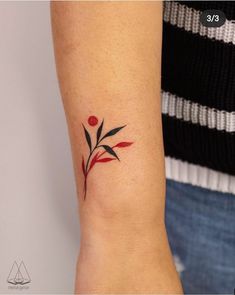 a woman's arm with a small red and black flower tattoo on the wrist