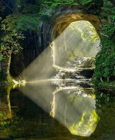 the sun shines through an arch over a river with water flowing from it's sides