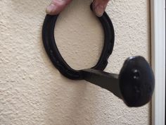 a person holding a pair of scissors in front of a white wall with a black handle