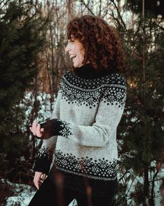 a woman standing in the snow with her hands on her hips and smiling at something