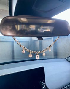 there is a gold chain attached to the rear view mirror in this car with charms on it