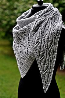 a knitted shawl on a mannequin in front of some trees and grass