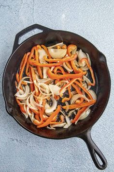 a skillet filled with onions and carrots on top of a blue countertop