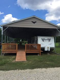 an rv is parked in the grass under a covered area with steps leading up to it