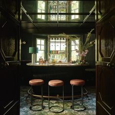 three stools sit in front of a bar with an open door leading into the room