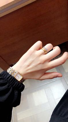 a woman's hand with two gold rings on her fingers and a black shirt