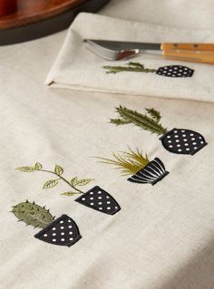 the table cloth has been embroidered with black and white designs on it, along with a knife and fork