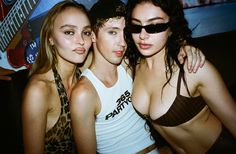 three young women posing for the camera in front of a poster