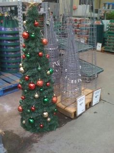 a small christmas tree sitting next to a wire cage in the middle of a store