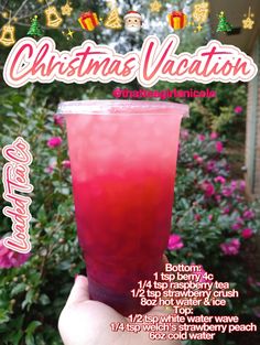 a hand holding up a pink drink in front of some bushes and flowers with the words christmas vacation on it