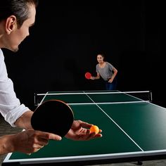 two people playing ping pong in the dark with one person looking at the ball