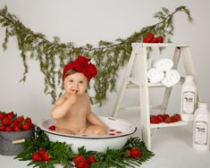 a baby sitting in a tub with strawberries