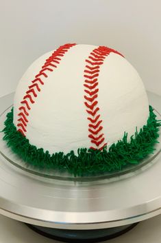 a baseball cake is decorated with green grass and red stitching on the bottom layer