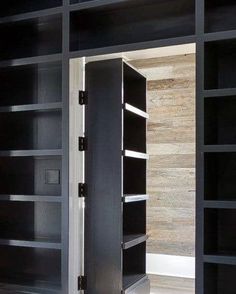 an open bookcase in a room with wooden floors and black shelving unit doors