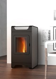 a black stove sitting on top of a wooden floor next to a white chair and wall