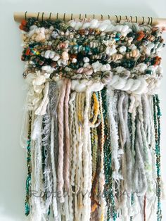 a wall hanging with many different colored beads and yarns on it's sides