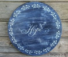 a blue plate with the word hope painted on it, sitting on a wooden surface