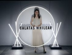 a woman standing in front of a white circle with the words galatass whilear on it