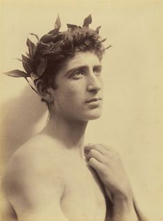 an old photo of a shirtless man with leaves on his head and hands to his chest