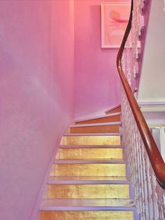 the stairs are painted pink and have wooden handrails that lead up to the second floor