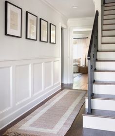 there is a stair case in the hallway with pictures on the wall and carpeted floor