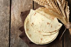 three tortillas on a napkin next to some ears of wheat