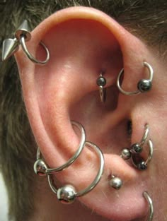 the man is wearing several different piercings on his ear