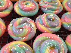 there are many different colored donuts on the cooling rack with sprinkles