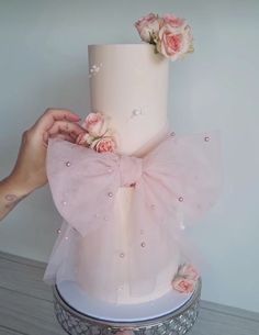 a woman is holding a pink cake with flowers on it