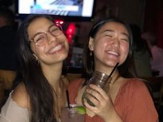 two women are smiling and holding drinks in their hands