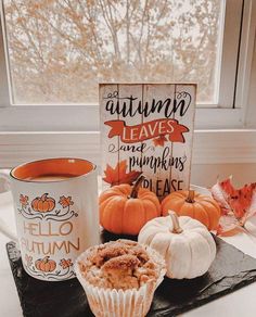 pumpkins and muffins on a tray next to a coffee cup with autumn leaves in the background