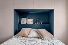 a bed with two pillows on top of it next to a blue shelf above the headboard