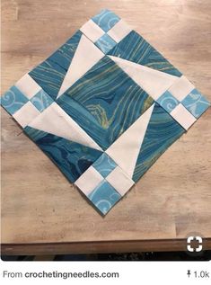 a piece of blue and white quilted material sitting on top of a wooden table