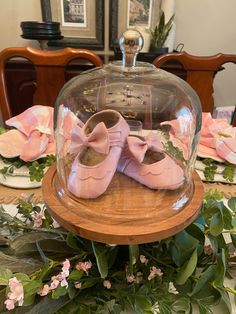 pink baby shoes under a glass dome on a table