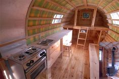 the interior of a tiny home with wood floors and walls, including a stove top oven