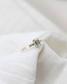 an engagement ring sitting on top of a white cloth