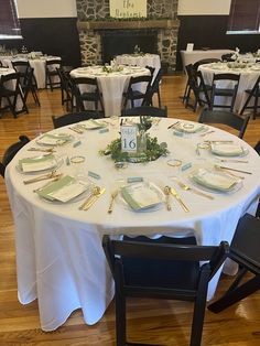 the table is set with plates and silverware for an elegant wedding reception at the stone fireplace