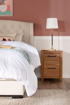 a white bed sitting next to a wooden night stand