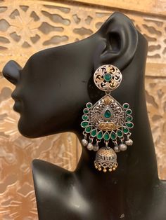 Gorgeous chandbali-jhumka design in pure brass (90%) and pure silver (10%) in two tone / dual tone / silver gold finish. Very beautiful design and craftsmanship. Available in red, blue, green, clear and multicolor stones. Care Instruction: Avoid heat & substances like perfume, deodorant, alcohol, etc and clean with silver/gold polish cloth. Store in airtight spaces like ziplock pouch or jewelry box. Ornate Chandbali Jhumkas With Oxidized Finish, Ornate Chandbali Oxidized Jhumkas, Ornate Oxidized Chandbali Jhumkas, Fusion Style Chandbali Brass Jhumkas, Silver Dual-tone Earrings For Navratri, Silver Brass Jhumkas With Tilla, Silver Dual-tone Chandbalis For Festivals, Dual-tone Chandbali Temple Jewelry Danglers, Dual-tone Chandbali Temple Danglers